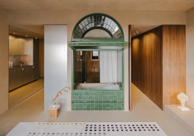 A modern, open-plan apartment in Barcelona featuring a central, arched bathtub integrated into the living space, designed by SIGLA Studio.