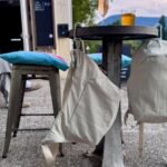 A Peak Design City Line crossbody bag with its innovative BagLev hook deployed, hanging from a cafe table, keeping the bag off the ground.