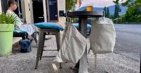 A Peak Design City Line crossbody bag with its innovative BagLev hook deployed, hanging from a cafe table, keeping the bag off the ground.