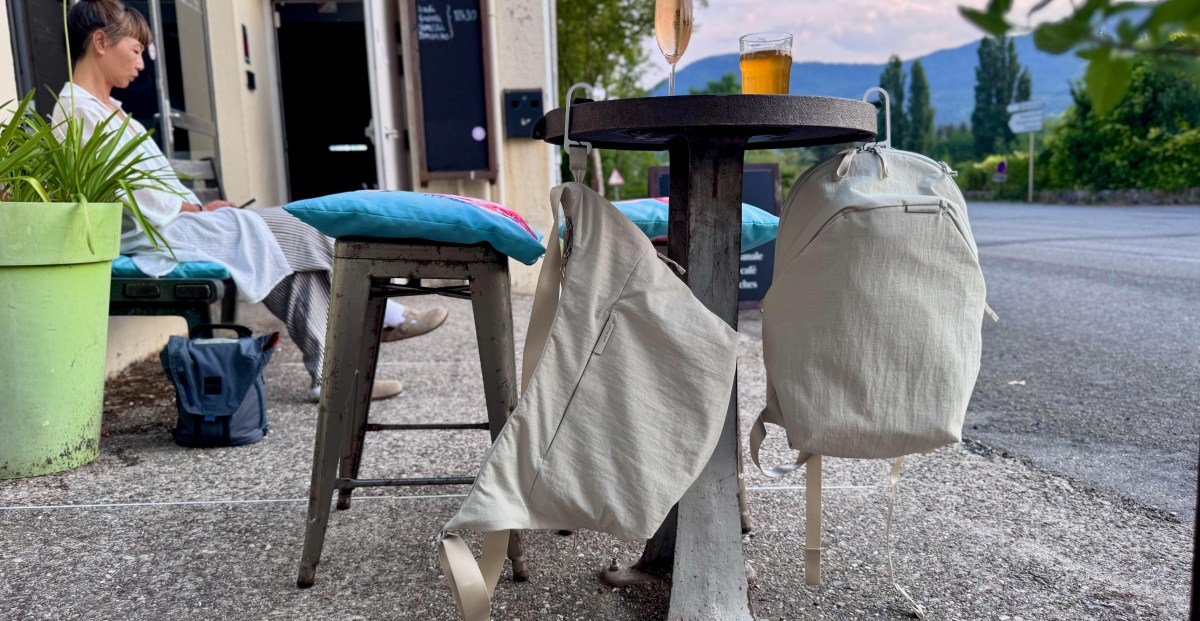 A Peak Design City Line crossbody bag with its innovative BagLev hook deployed, hanging from a cafe table, keeping the bag off the ground.