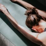 A person demonstrating a PNF stretch on a yoga mat, focusing on hamstring flexibility.