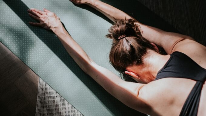 A person demonstrating a PNF stretch on a yoga mat, focusing on hamstring flexibility.