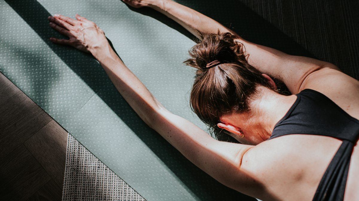 A person demonstrating a PNF stretch on a yoga mat, focusing on hamstring flexibility.