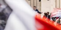 Jean-Luc Mélenchon s'exprimant lors d'un meeting politique, avec un fond aux couleurs de la France Insoumise, symbolisant son ambition pour 2027.