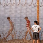 Des migrants, incluant femmes, hommes et enfants, tentent de franchir la frontière de Sebta, illustrant les défis de la mobilité humaine entre l'Afrique et l'Europe.