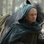 Aegon Targaryen standing before his dragon Sunfyre, who is scarred but alive, emerging from the woods in House of the Dragon Season 3.