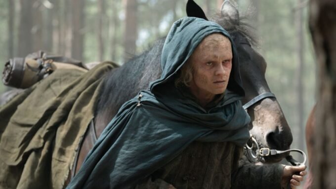 Aegon Targaryen standing before his dragon Sunfyre, who is scarred but alive, emerging from the woods in House of the Dragon Season 3.