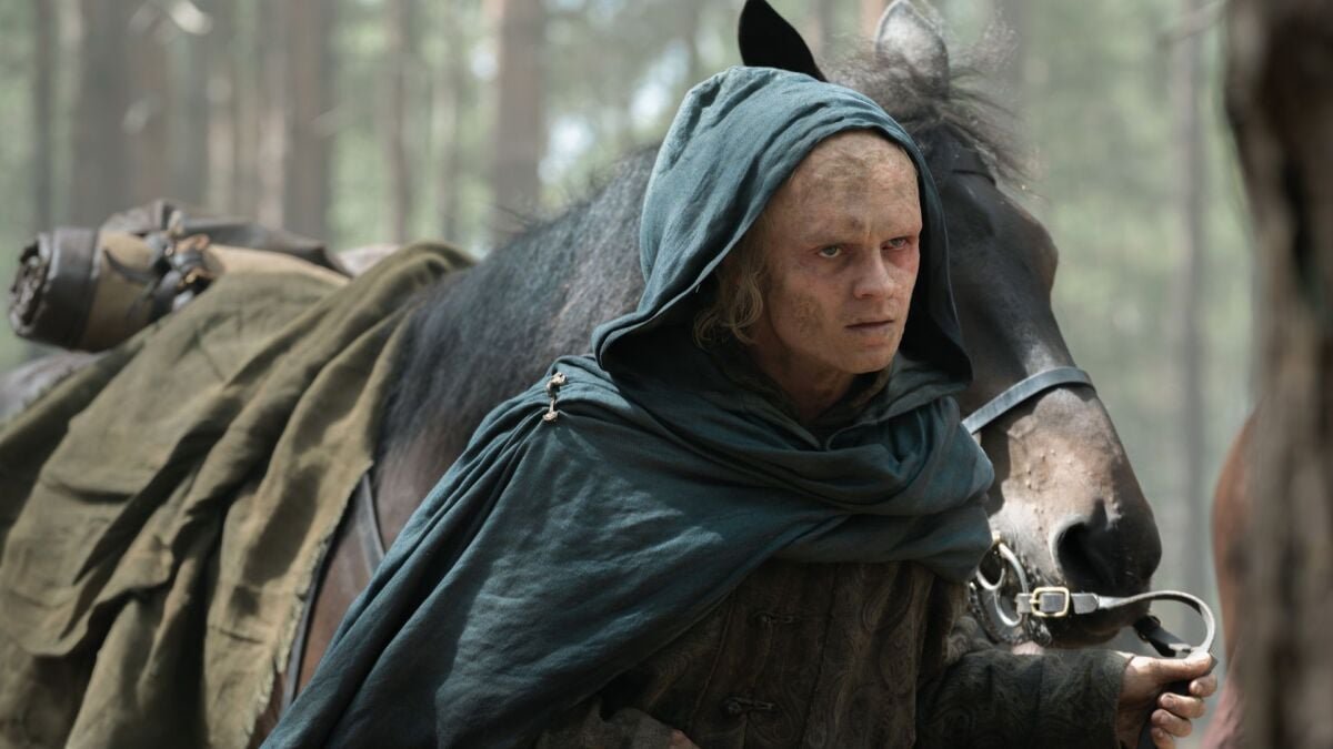 Aegon Targaryen standing before his dragon Sunfyre, who is scarred but alive, emerging from the woods in House of the Dragon Season 3.