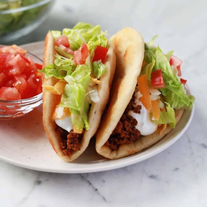 Homemade Taco Bell Chalupa Supreme with seasoned ground beef, sour cream, cheese, lettuce, and tomatoes, served on a crispy fried shell.
