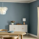 Valspar's 2027 Color of the Year, Cottage Door, a mid-tone blue, featured in a modern living space with warm gray and creamy pink accents.