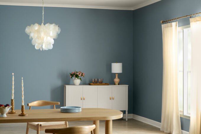 Valspar's 2027 Color of the Year, Cottage Door, a mid-tone blue, featured in a modern living space with warm gray and creamy pink accents.