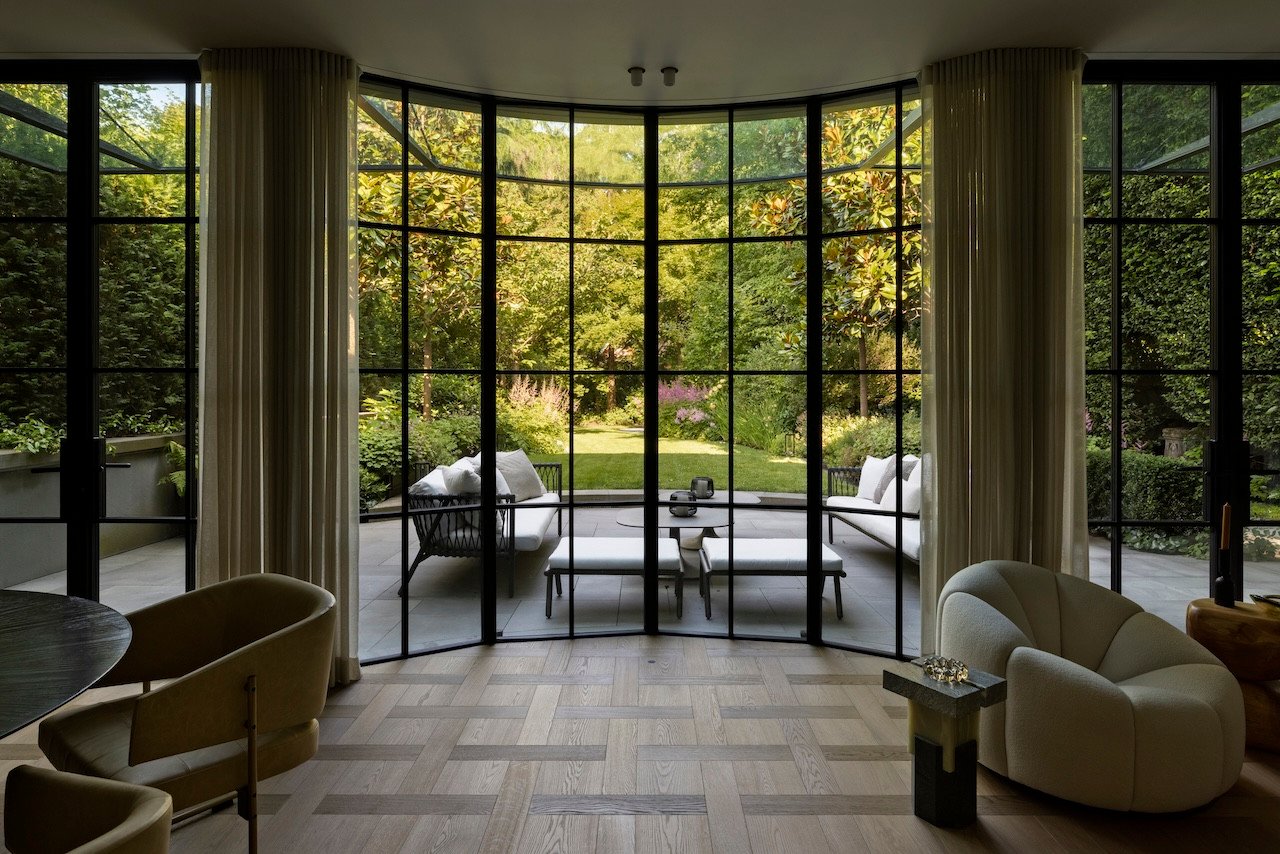 Exterior view of a modern Vancouver home addition featuring floor-to-ceiling glass, seamlessly integrating with the surrounding garden, photographed by Ema Peter.