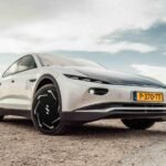Voiture Électrique : L'Énergie Solaire, du Gadget Embarqué à la Révolution Domiciliaire 8 Une voiture électrique moderne garée devant une maison équipée de panneaux solaires sur le toit, symbolisant la recharge solaire domestique et l'intégration des énergies renouvelables dans la mobilité.