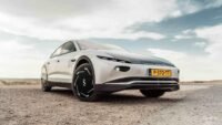 Une voiture électrique moderne garée devant une maison équipée de panneaux solaires sur le toit, symbolisant la recharge solaire domestique et l'intégration des énergies renouvelables dans la mobilité.