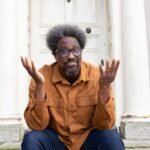 W. Kamau Bell, comedian and activist, holding a smartphone charger, representing his most indispensable tool.