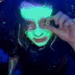 Still from 'We’re All Going to the World’s Fair' showing a young girl staring intensely into a webcam, bathed in screen light.