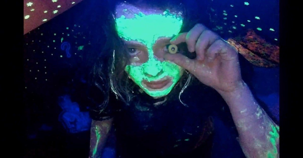 Still from 'We’re All Going to the World’s Fair' showing a young girl staring intensely into a webcam, bathed in screen light.