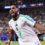 Riyad Mahrez en maillot de football, potentiellement retouché aux couleurs du Wydad de Casablanca, ou une image générique de lui en action.