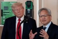 Donald Trump speaking on a phone with Jensen Huang, CEO of Nvidia, on a large screen at a tech summit.