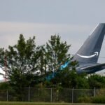 Emergency services at the scene of an Amazon Prime Air cargo plane crash at Miami International Airport, with debris scattered and smoke visible.