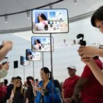 Attendees photograph the new iPhone Duo at an Apple event, symbolizing the technology at the heart of the patent dispute.
