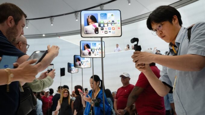 Attendees photograph the new iPhone Duo at an Apple event, symbolizing the technology at the heart of the patent dispute.