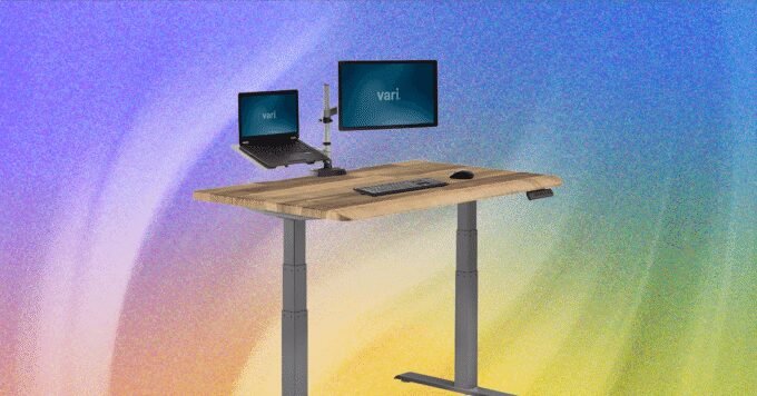 A modern standing desk with a computer setup, transitioning between sitting and standing positions.