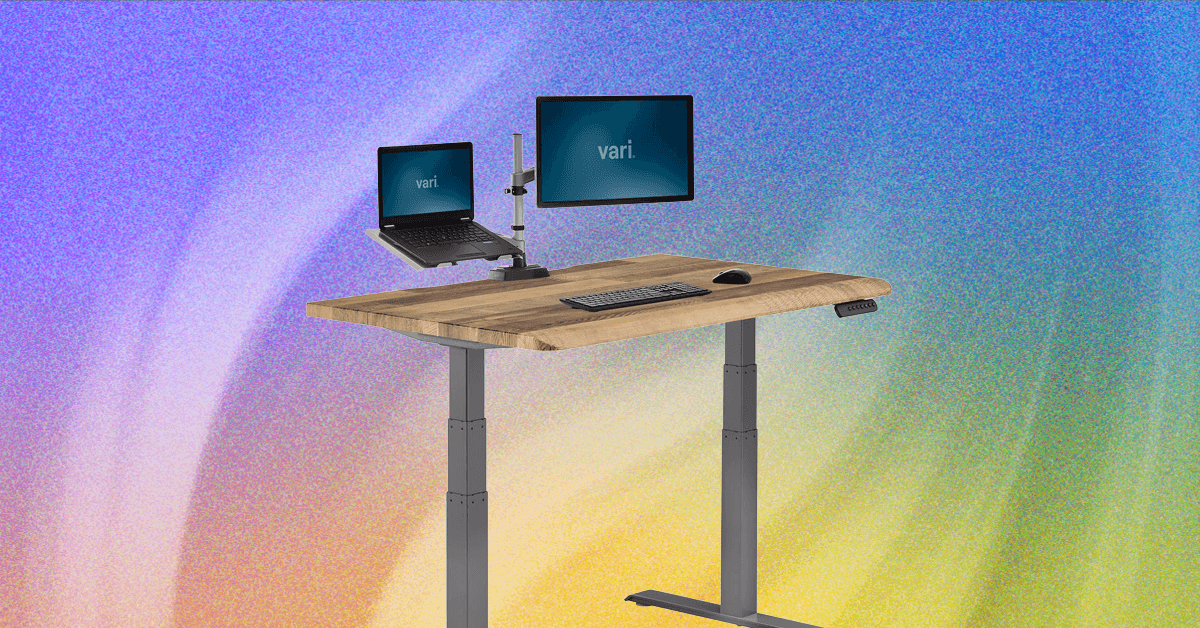 A modern standing desk with a computer setup, transitioning between sitting and standing positions.