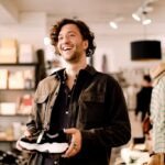 Beyond the Welcome Mat: Mastering the Art of Unforgettable First Impressions for Your Business 8 A customer walking into a well-lit, inviting business space, with a friendly staff member in the background.