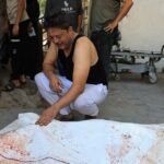 أب فلسطيني يبكي بجانب جثمان ابنه محمد عبد الزناتي في مستشفى الشفاء بغزة بعد ضربة جوية إسرائيلية.