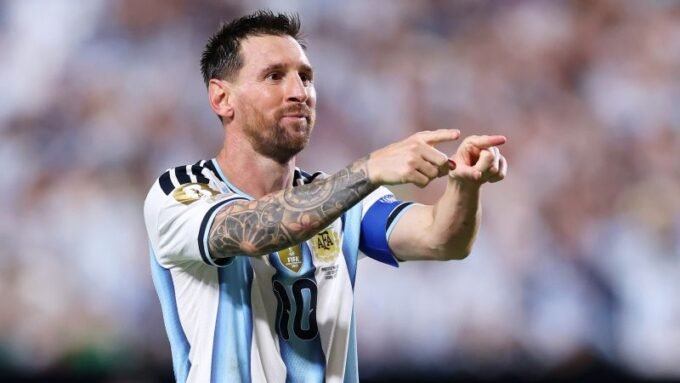 ليونيل ميسي يرتدي قميص منتخب الأرجنتين ويحيي الجماهير في ملعب كرة قدم.