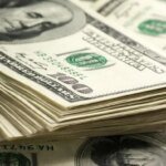 صورة توضيحية لعملة الدولار الأمريكي مع رسوم بيانية تظهر ارتفاع قيمتها في سوق العملات العالمية.