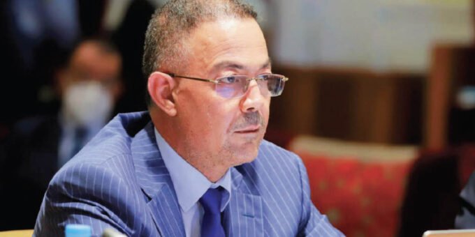 Fouzi Lekjaa s'exprimant devant un auditoire de la CGEM, avec le logo du PAM en arrière-plan, symbolisant l'engagement du parti sur la fiscalité des entreprises et la lutte contre l'informel.