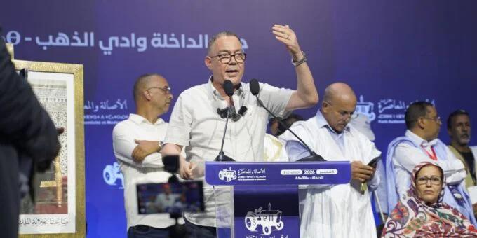 Fouzi Lekjaa, membre du bureau politique du PAM, s'exprimant lors d'une rencontre à Dakhla, avec le logo du parti en arrière-plan.