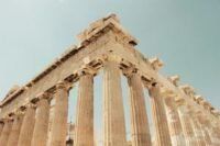Panoramic view of the majestic Acropolis in Athens at sunset, with the city lights twinkling below.