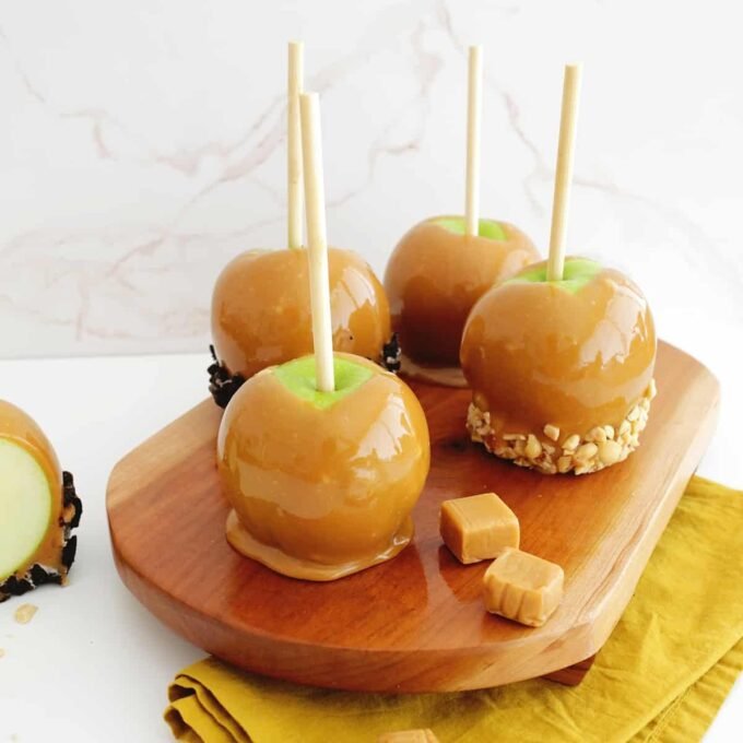 A perfectly coated caramel apple adorned with various toppings like nuts, sprinkles, and chocolate, ready to be enjoyed.