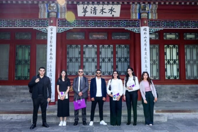 Groupe de doctorants marocains souriants en formation technologique en Chine, avec des représentants de Huawei et du Ministère de l'Enseignement Supérieur en arrière-plan.