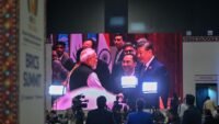 Indian Prime Minister Narendra Modi and Chinese President Xi Jinping meeting during the 18th BRICS Summit in New Delhi, displayed on a large digital screen.