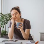 Beyond Iron: Could a Vitamin D Deficiency Be Sabotaging Your Energy Recovery? 6 A tired woman looking at a blood test result, considering the link between iron deficiency and vitamin D.