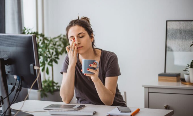 A tired woman looking at a blood test result, considering the link between iron deficiency and vitamin D.