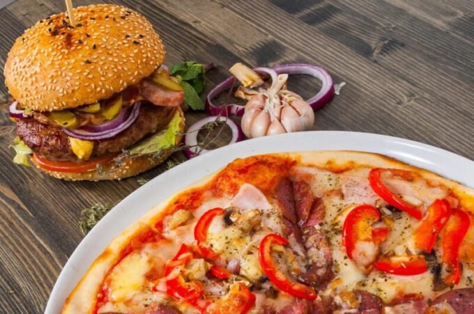 Une table de repas au Maroc, présentant un mélange de plats traditionnels riches en légumes et fruits, et d'aliments modernes plus gras et sucrés, illustrant la transition nutritionnelle.