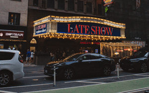 A collage or graphic representing various late-night talk show hosts and their iconic sets, symbolizing the enduring spirit of late-night television.