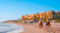 Vue panoramique du Mazagan Beach & Golf Resort au coucher du soleil, avec la plage et le parcours de golf en arrière-plan, illustrant une évasion luxueuse et relaxante.