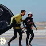 Vue aérienne de la médina d'Essaouira et de sa plage, avec des festivaliers profitant de la musique électronique en plein air, symbolisant les 10 ans du MOGA Festival.