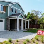 A drone view of a "sold" sign next to a newly built single-family home in a coastal development, symbolizing the dynamic housing market.