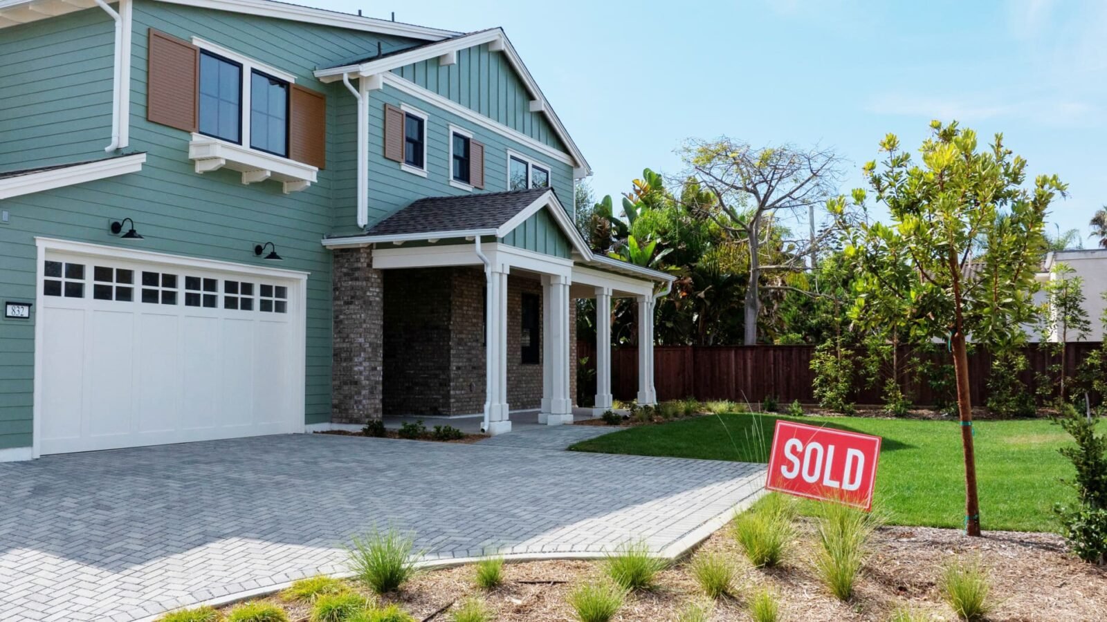 A drone view of a "sold" sign next to a newly built single-family home in a coastal development, symbolizing the dynamic housing market.