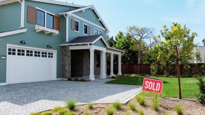A drone view of a "sold" sign next to a newly built single-family home in a coastal development, symbolizing the dynamic housing market.