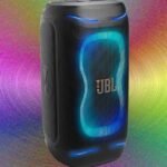 A vibrant party speaker with LED lights, playing music at a lively gathering, showcasing its portability and powerful sound.