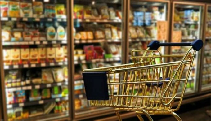 Un consommateur examine attentivement les prix dans un rayon de supermarché, symbolisant la pression sur le pouvoir d'achat en France.