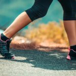 Personne souriante faisant du sport en extérieur au lever du soleil, symbolisant la joie et la vitalité de la reprise sportive.